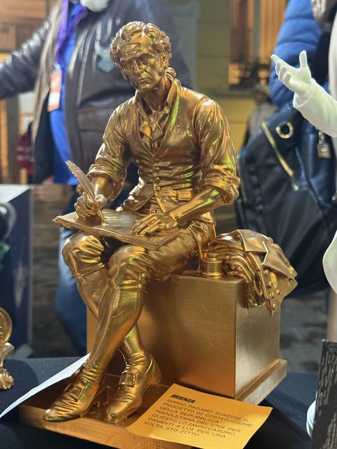 Mario Pagano, scultura dorata, seduto mentre scrive